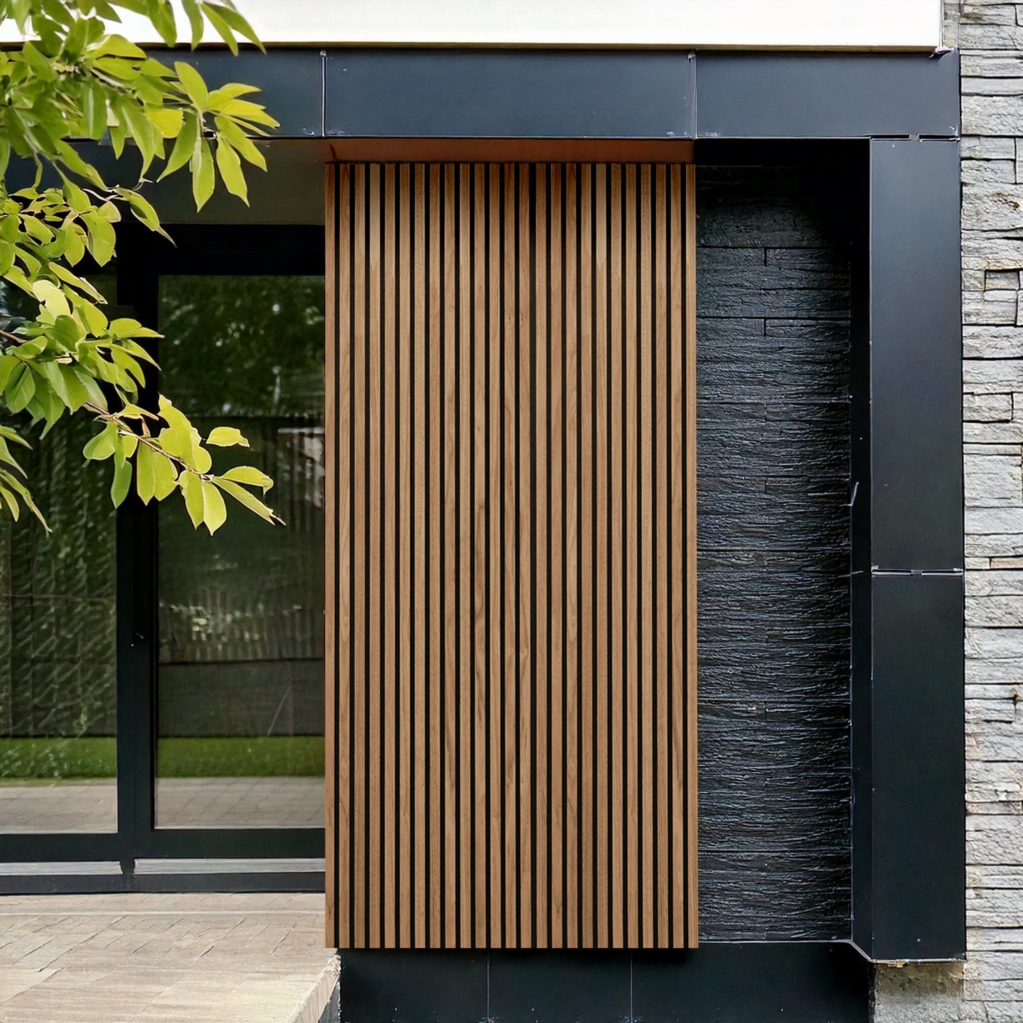Modern building facade with Teak Color Exterior WPC Panel by Landmark Decor, vertical wooden slats look and black metal framing, weather-resistant panels, gray stone wall, glass door partially visible; tree leaves in foreground.