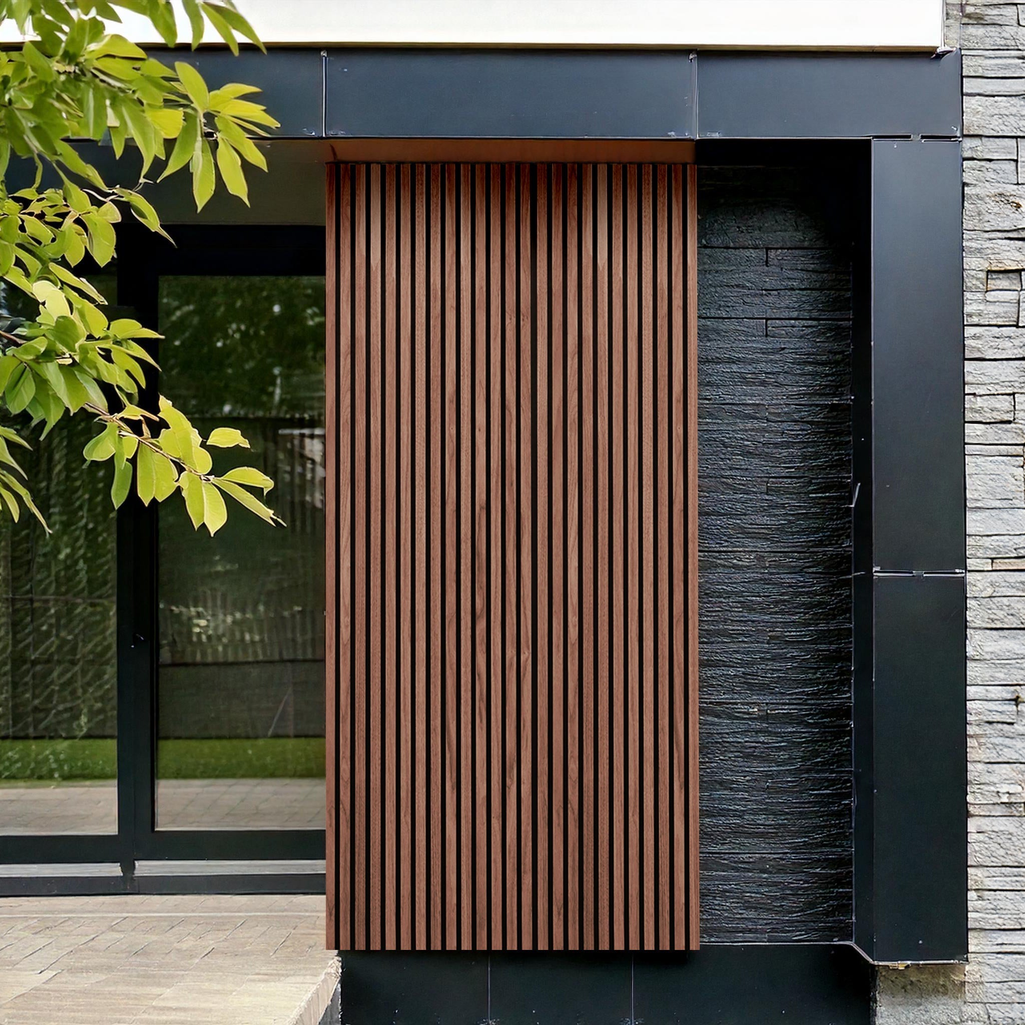 Landmark Decor's Redwood Exterior WPC Panel adds weather-resistant vertical wood detail beside a glass door, with black metal framing and gray stone cladding, creating a striking outdoor wall accent beneath overhanging tree branches.