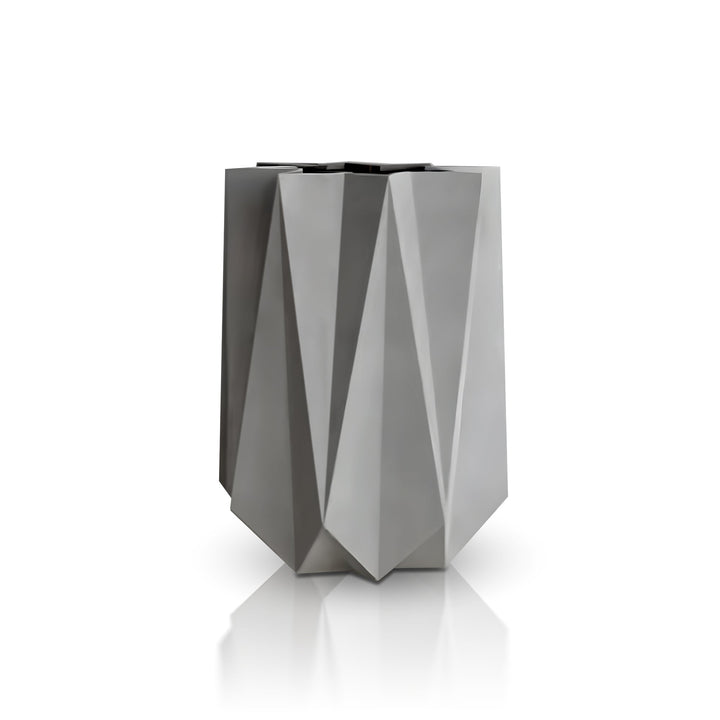 The Visione Astratta Elegant Planter by Landmark Decor is a sleek, modern vase with a geometric, faceted surface in matte gray. Its tall, angular design complements handmade planters and casts subtle reflections against the glossy surface set on a clean white background.